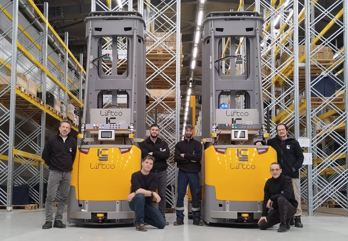 Thanassis Papaleloudis, the CEO of Liftco, with more of the company’s staff, alongside two of its ANT driven VNA AGVs.