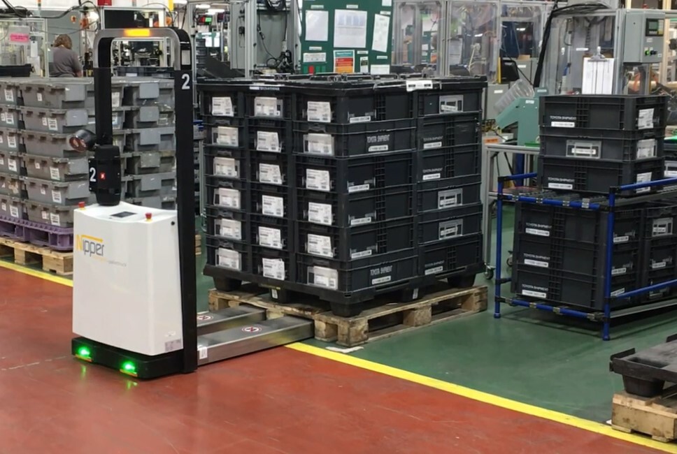 An AGV picking up a pallet of finished goods in a warehouse.